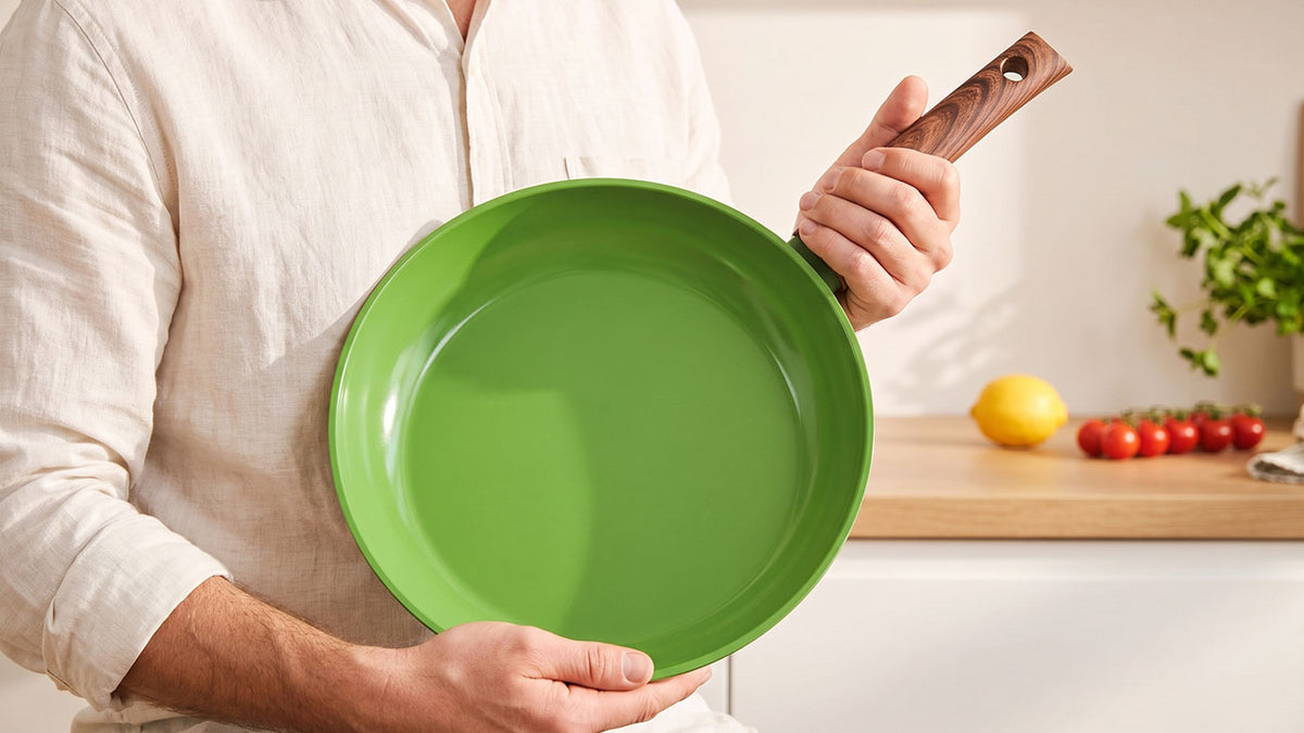 Man houdt groene Go Green keramische koekenpan vast in de keuken