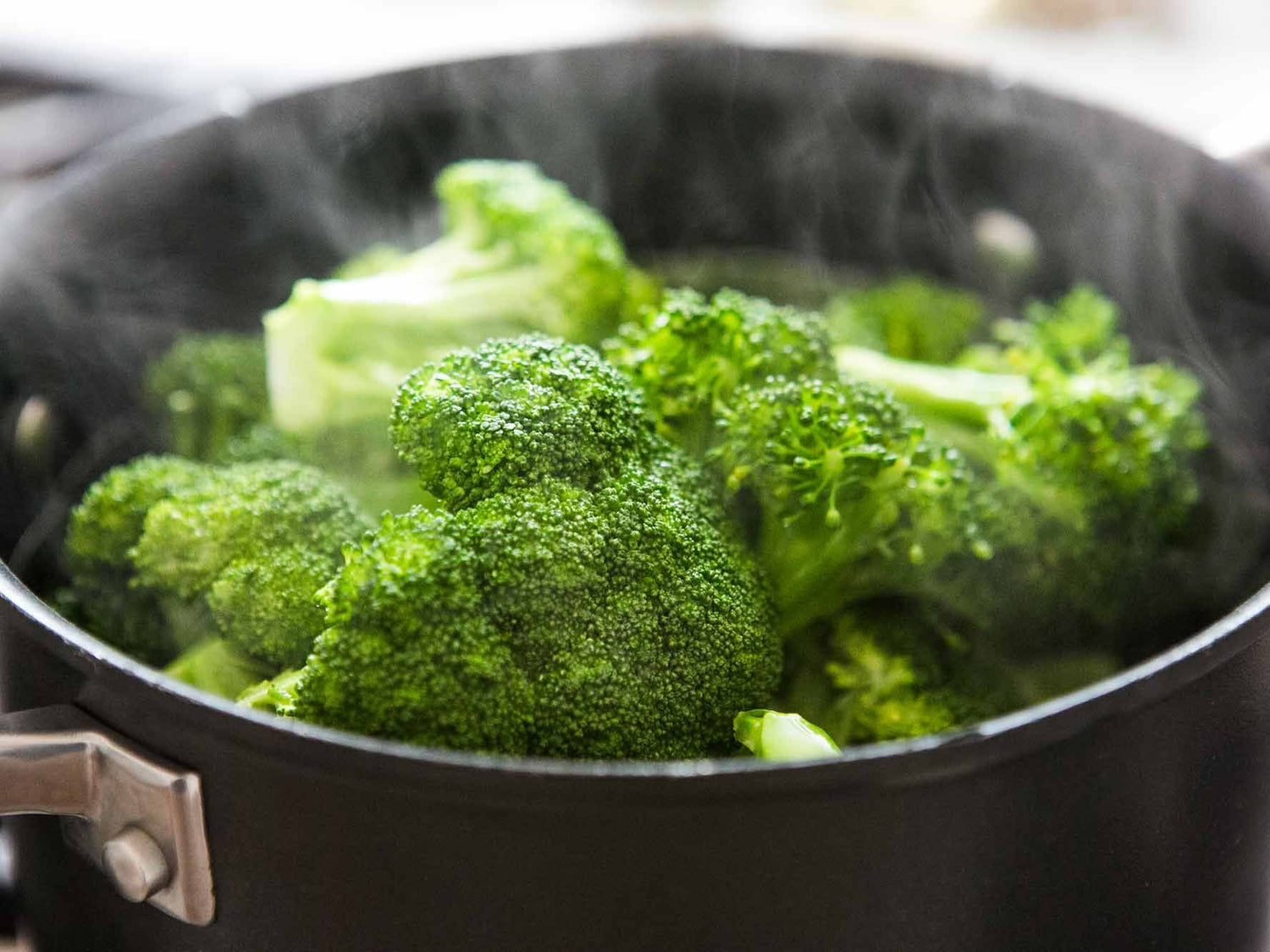 Pan met kokend water en groene broccoliroosjes klaar voor het serveren