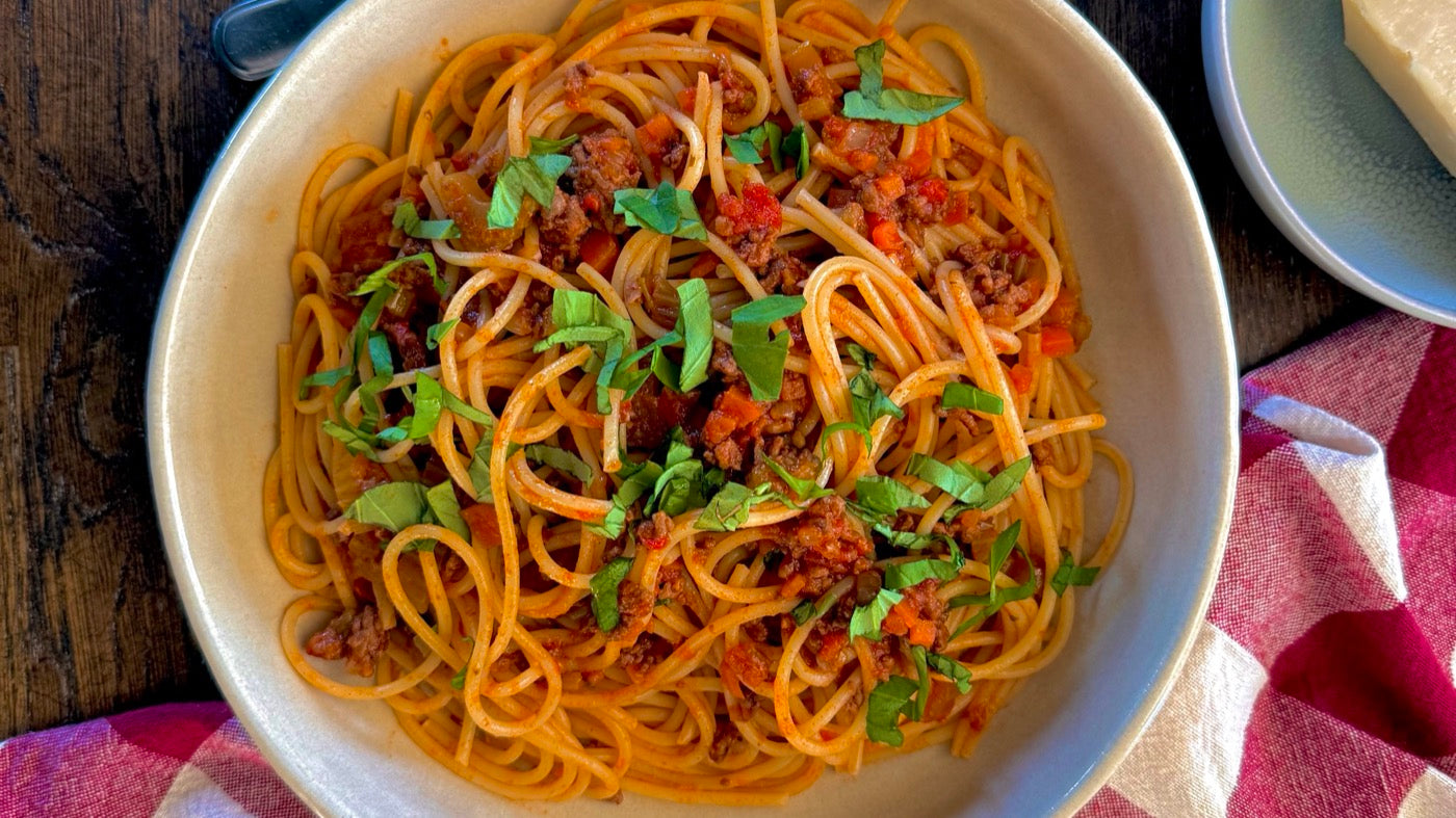 Spaghetti bolognese met verse basilicum in een beige bord