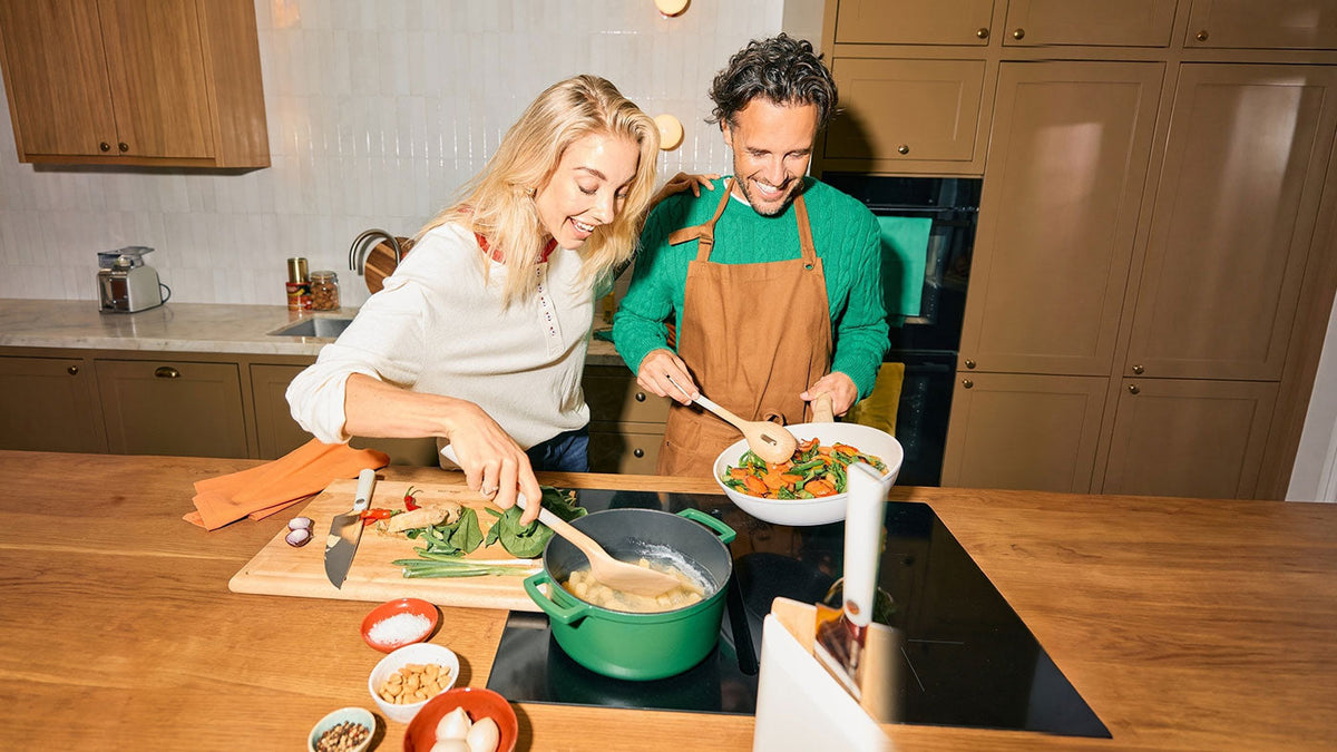 Stel kookt samen met een groene braadpan en witte keramische wokpan