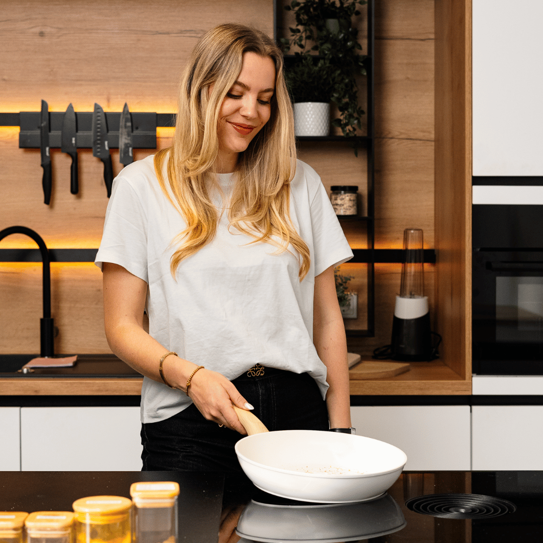 Ensemble de deux poêles blanches avec poignée en bois, femme cuisine dans une cuisine moderne.