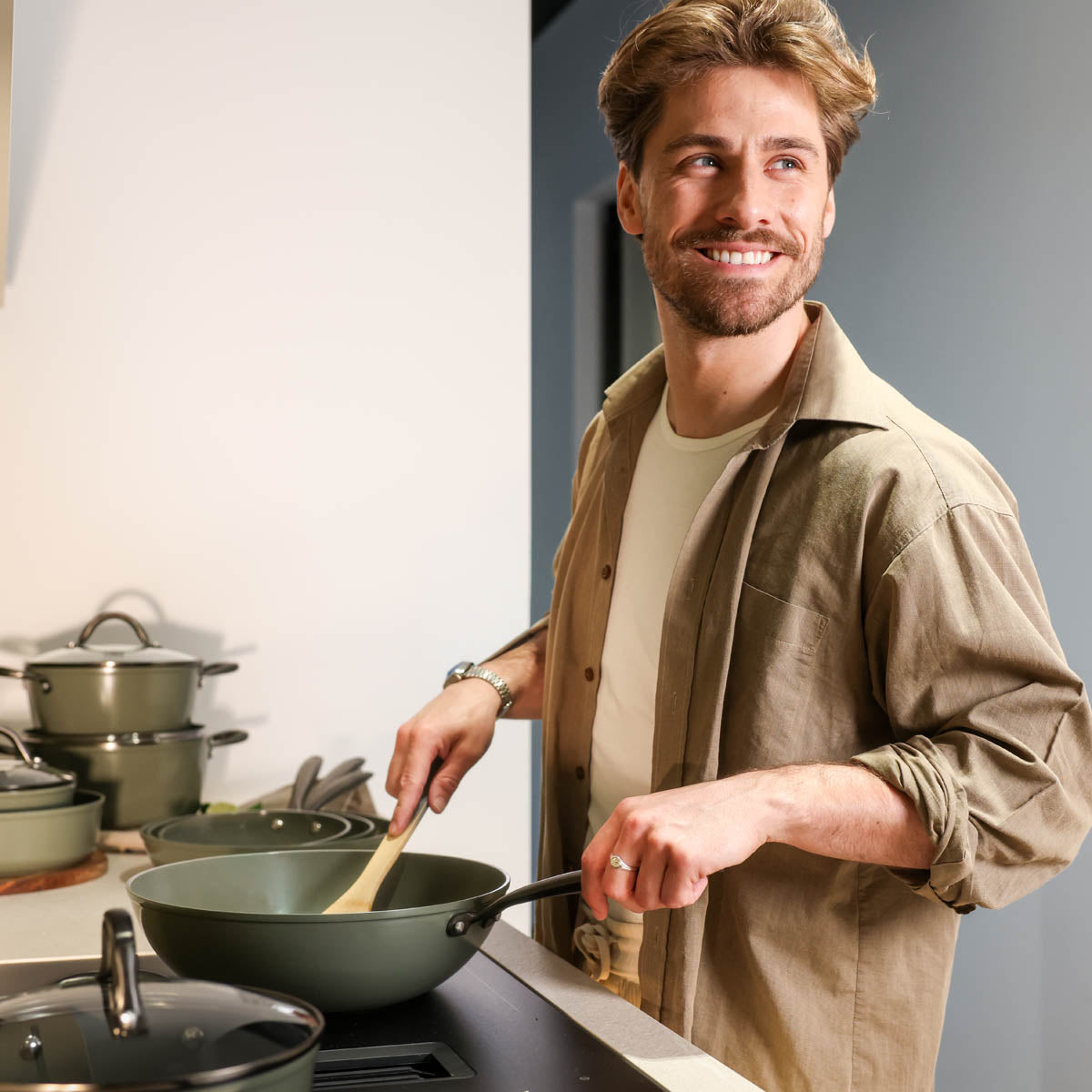 Donkergroene 9-delige pannenset met glazen deksels en roestvrijstalen handgrepen, gebruikt in moderne keuken.