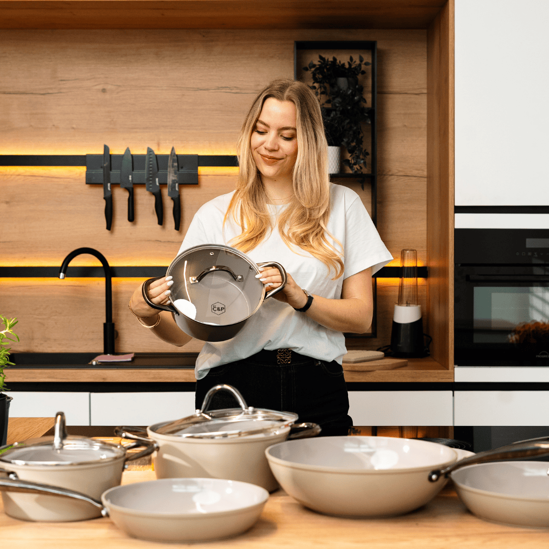 Pannenset van negen stuks in taupe met glazen deksels en zwarte handgrepen in moderne keukenomgeving.