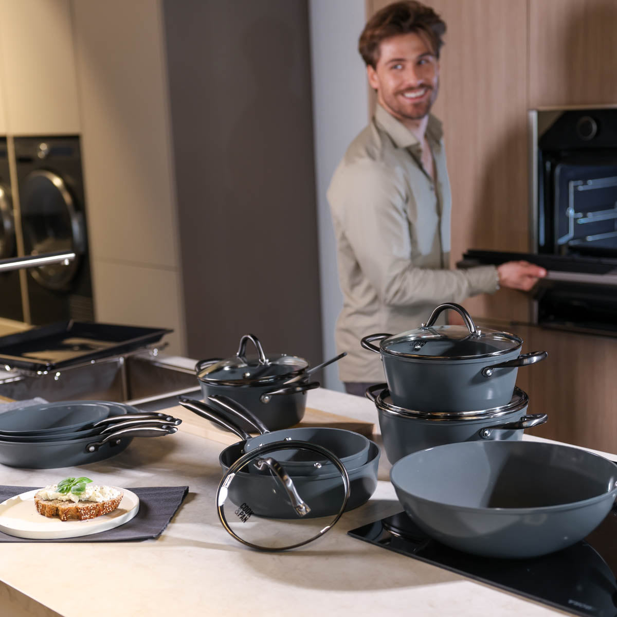 Black 9-piece cookware set with glass lids and matte finish, various sizes and shapes.