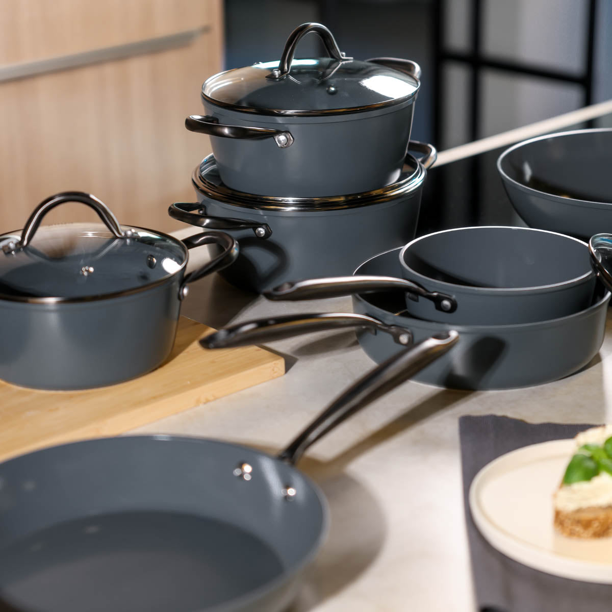 Nine-piece black cookware set made of durable material with glass lids and stainless steel handles.
