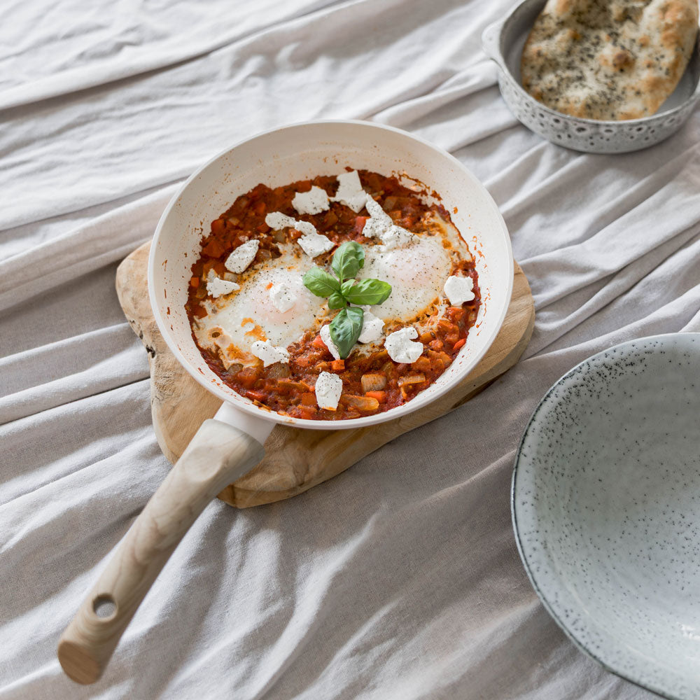 Ensemble de trois poêles beige clair avec poignée en bois, dont une remplie d'un plat de tomates et de fromage.