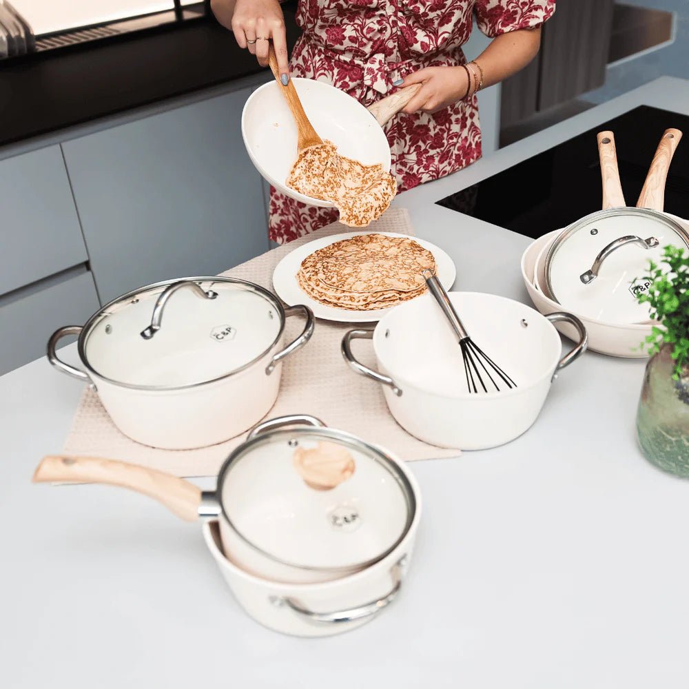 White cookware set with glass lids and wood-colored handles, excluding tableware and accessories.