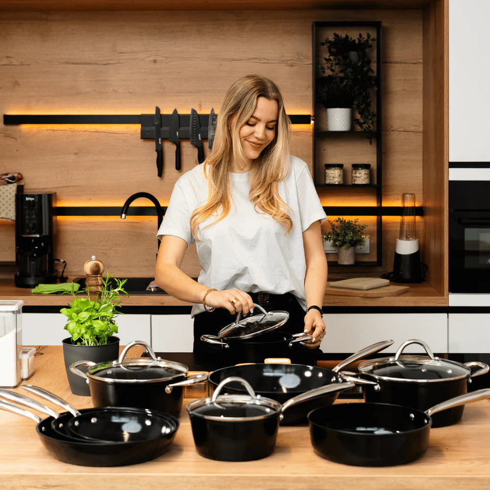 Schwarzes 3-teiliges topfset und pfannenset mit Glasdeckeln auf modernem Holzarbeitsplatte.