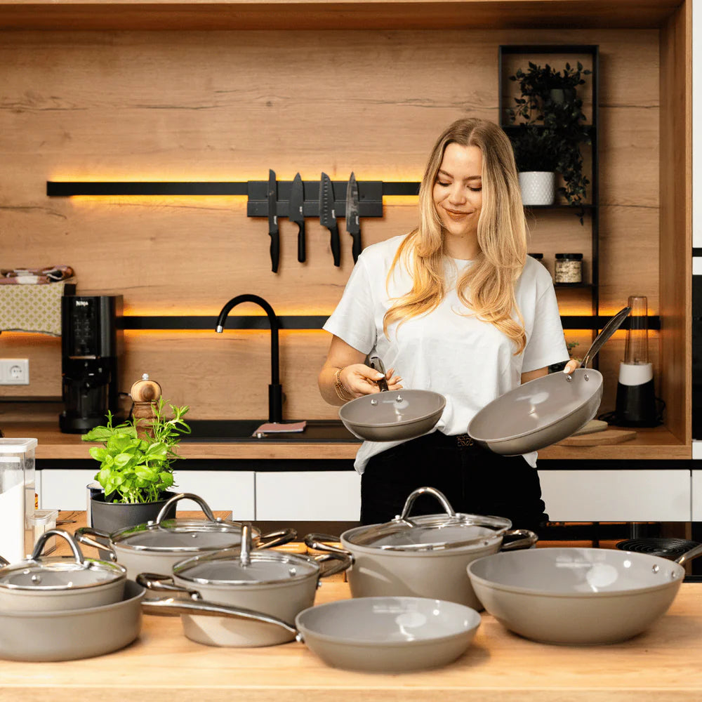 Woman in kitchen with Taupe cookware set on counter