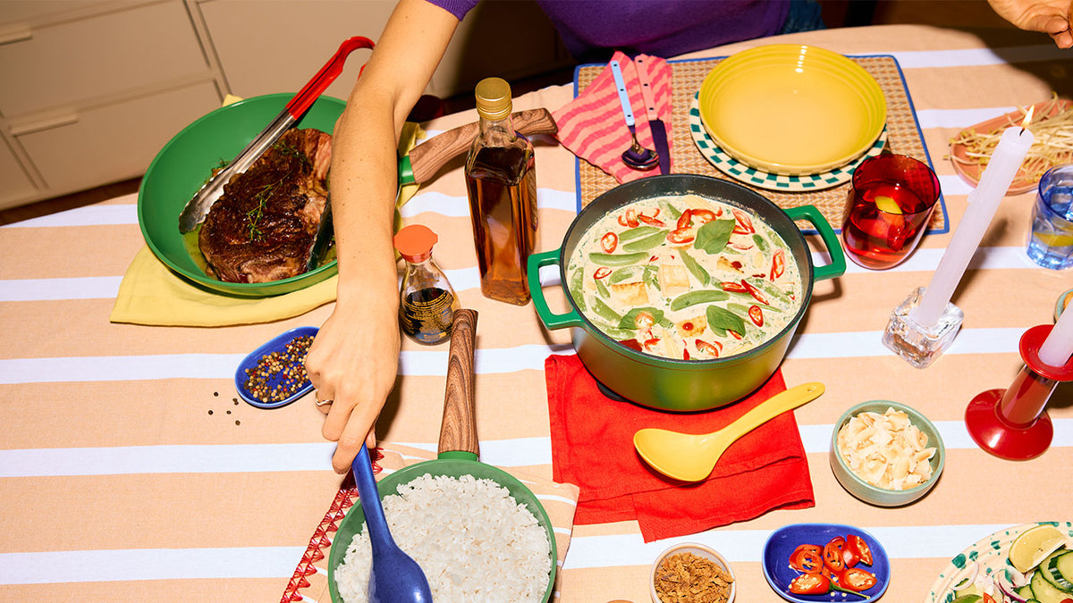 Gedekte tafel met groene curry in een groene gietijzeren braadpan