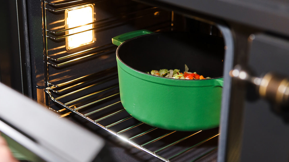 Groene gietijzeren braadpan met groenten in de oven