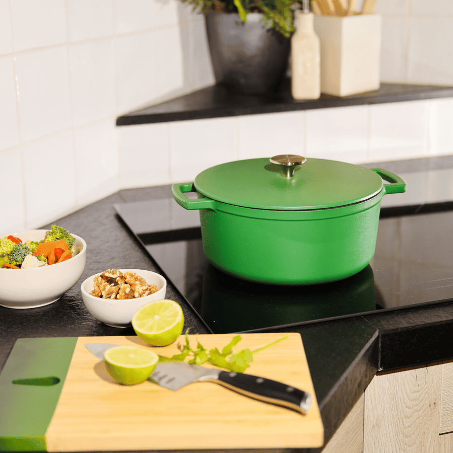 Casserole verte en métal avec couvercle sur une plaque à induction noire dans une cuisine moderne.