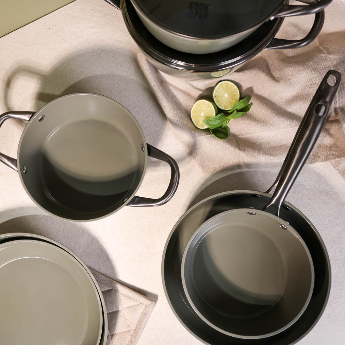 Batterie de cuisine vert foncé 9 pièces avec revêtement antiadhésif et poignées noires.