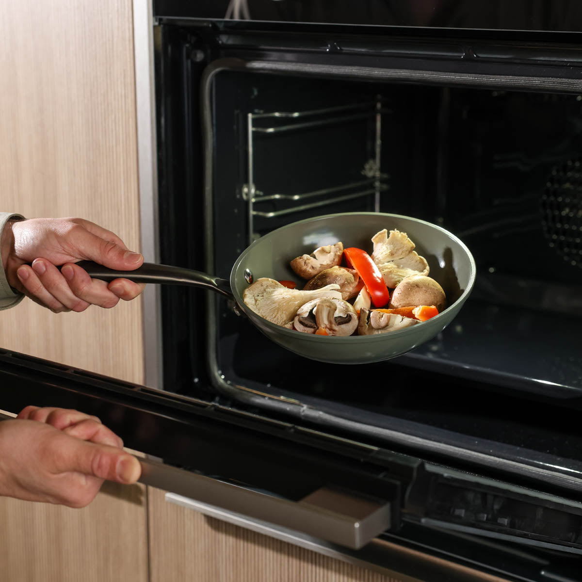Dark green frying pan 20 cm with non-stick coating and black handle, in use with vegetables in oven.