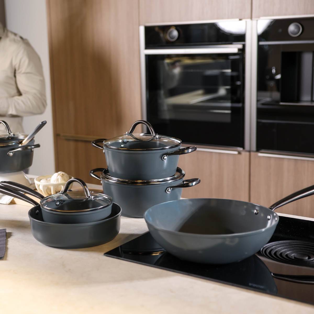 Gray 9-piece cookware set with glass lids and stainless steel handles on a black induction cooktop.