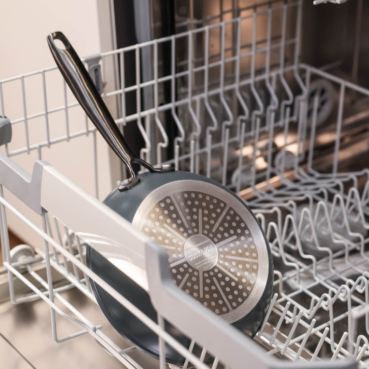 Black cookware set with stainless steel handles and cross-shaped base for induction cooking in the dishwasher.