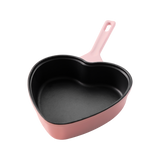 Roze gietijzeren koekenpan in hartvorm met zwarte binnenkant, 20 cm breed.