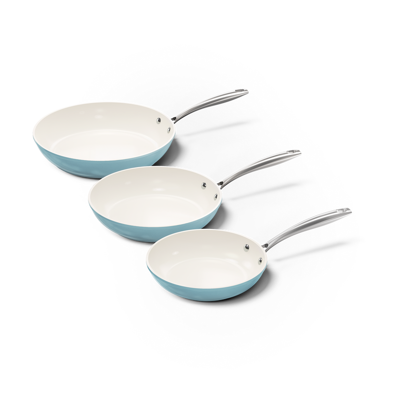 Set de trois poêles bleu clair avec intérieur en céramique blanche et poignées métalliques.