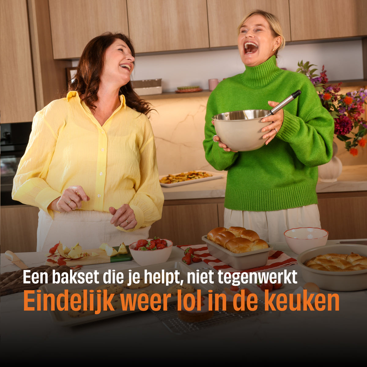 Zwei Frauen lachen in einer Küche mit einem Taupe of Mind Backset, eine hält eine Rührschüssel