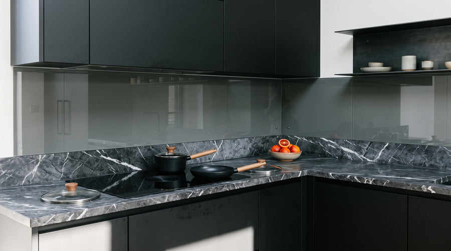 Cuisine industrielle avec des façades noir mat et des casseroles et poêles noires sur marbre foncé